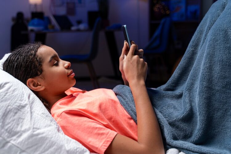 Teenage girl using a smartphone in bed