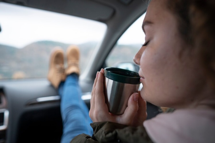 Side view of a woman in a car holding a drink